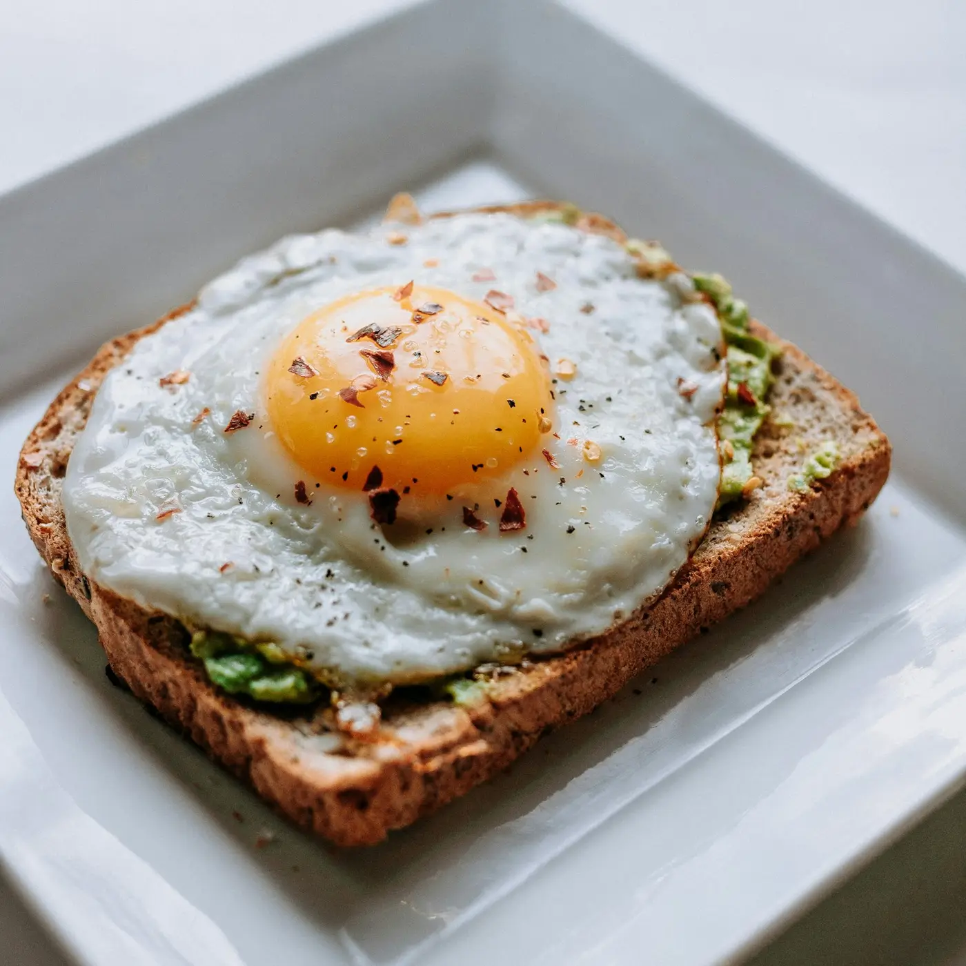 A fried egg on toast on a white plate