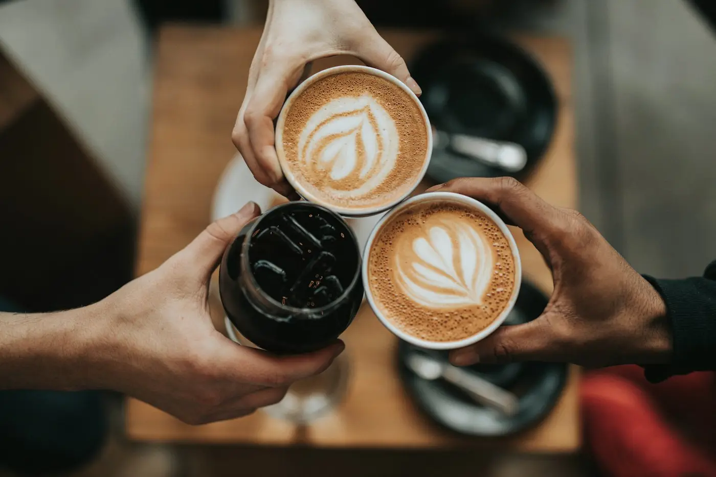 Three coffees raised together over the table