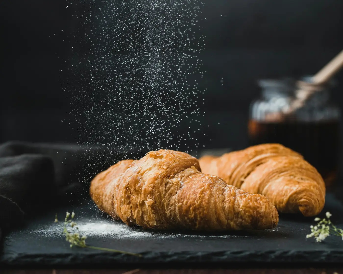 Pastries dusted with icing sugar on a dark slate counter